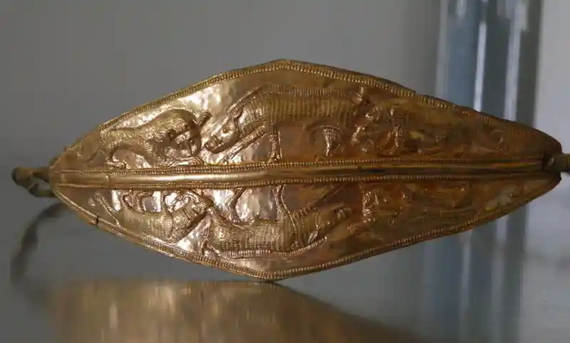 A gold bracelet with an animal design. A gold bracelet with an animal design.